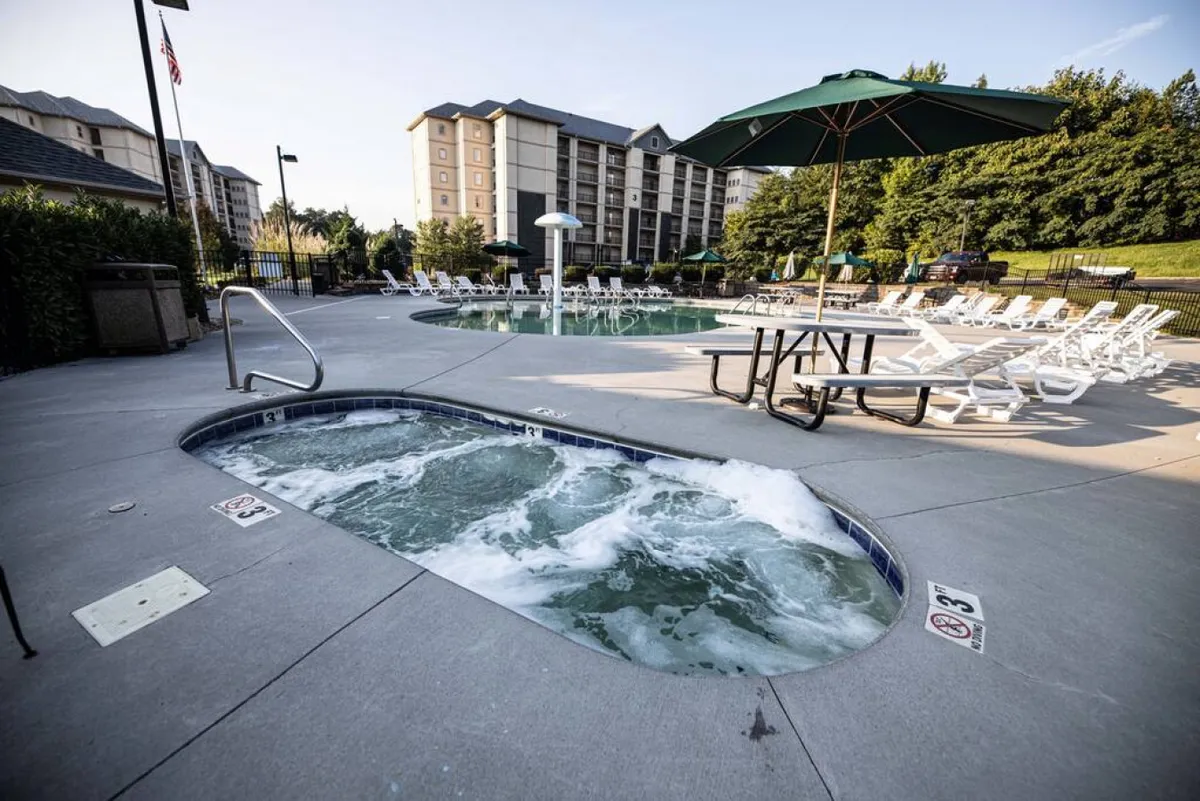 A spacious outdoor area showcases a sparkling swimming pool, adjacent hot tub, picnic tables, and lounge chairs. The space is welcoming and set up for both relaxation and socializing, making it ideal for families to swim, sunbathe, or gather for meals.